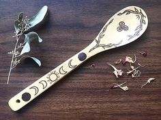 a wooden spoon sitting on top of a table next to some dried flowers and leaves