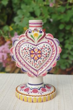 a heart shaped vase sitting on top of a table