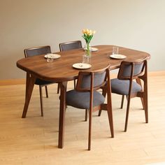 a wooden table with four chairs and a vase filled with flowers on top of it