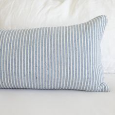 a blue and white striped pillow sitting on top of a bed