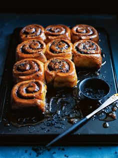 some cinnamon rolls are on a black tray