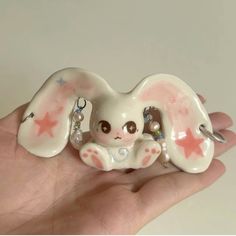 a hand holding a small white elephant figurine with pink stars on it's ears