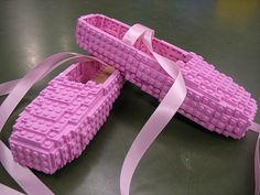 two pieces of pink lego style shoes are on a table with a ribbon around them