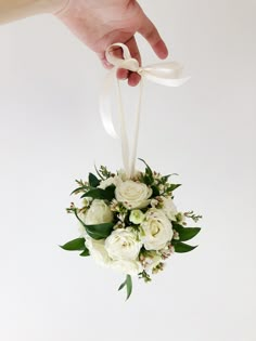 a bouquet of white flowers is being held by a person's hand on a white background