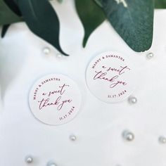 two wedding stickers with the names of their bride and groom on them next to some green leaves