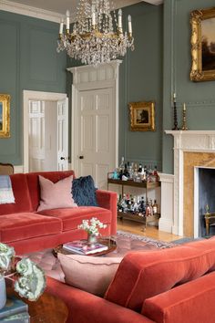 a living room filled with red couches and a chandelier above a fire place