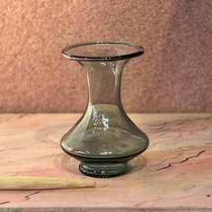 a small glass vase sitting on top of a table next to a wooden pen and paper