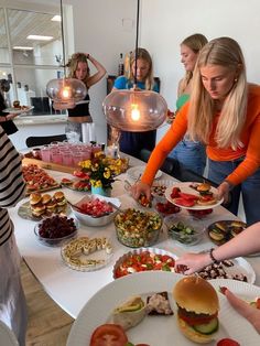 a group of women standing around a table filled with food