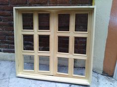 a wooden window sitting on top of a cement floor next to a brick wall in front of a building