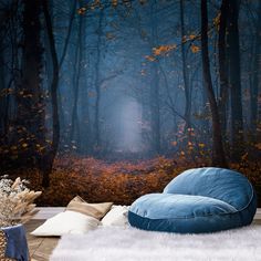 a blue bean bag chair sitting on top of a white rug in front of a forest wall mural