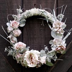 a wreath with flowers and greenery hanging on a wooden wall