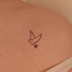 a small bird tattoo on the back of a woman's left side ribcage