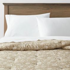 an unmade bed with white linens and brown headboard in a hotel room