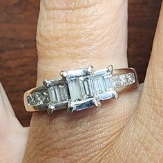 a woman's hand with a three stone diamond ring on top of her finger