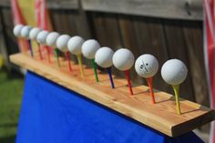 several golf balls are lined up on a wooden rack with colored tees in front of an american flag