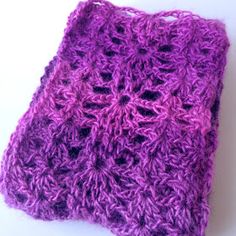 a purple crocheted square sitting on top of a white table