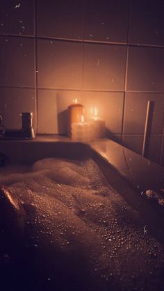 a bathtub filled with water next to a candle