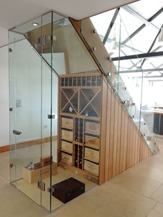 a wine cellar in the middle of a room with glass walls and stairs leading up to it