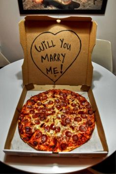 a pizza in a box with the words will you marry me written on it