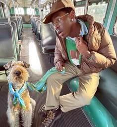 a man sitting on a bus with a small dog in his lap and looking at the camera