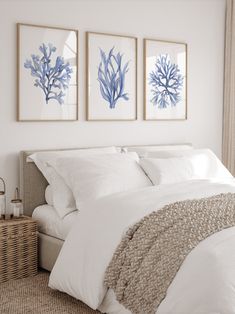 three blue and white paintings hang above a bed