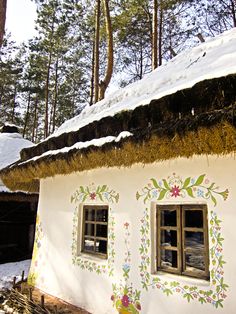 a white house with flowers painted on it's side and two windows in the front