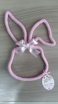 a pink dog leash with a white bow and name tag on it's side