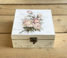 a white box with flowers painted on the lid and bottom is sitting on a wooden surface