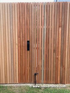 a wooden fence with a black latch on it's side and grass in the foreground