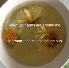 a white bowl filled with soup and two yellow flowers on it's side that says, when your arms are around me i'd swear that i'm holding the sun