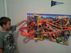 a young boy is playing with his toy train set on the wall in front of him