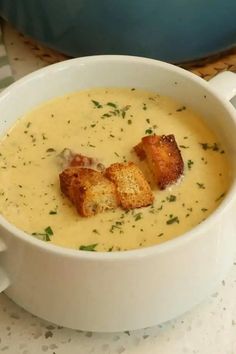 a white bowl filled with soup and croutons