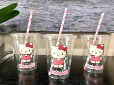 three hello kitty cups with pink and white straws in them sitting on a table