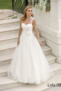 a woman in a white wedding dress standing on some steps with her hands in her pockets