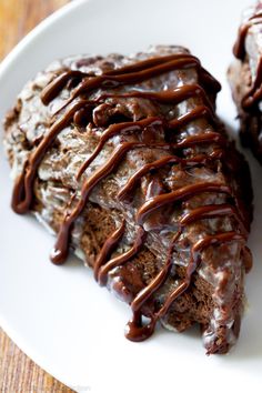 a white plate topped with chocolate scones covered in icing