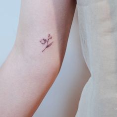 a woman's arm with a small flower tattoo on the left side of her arm