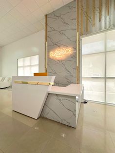 an office lobby with marble walls and white counter tops, along with a neon sign on the wall