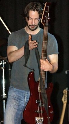 a man standing next to a red guitar