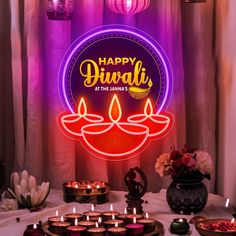 there are many lit candles on the table with flowers in front of it and a sign that says happy diwali at the same time