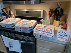 pizza boxes are stacked on top of the stove