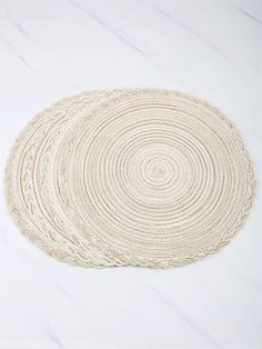 the white placemats are arranged on top of each other, and one is made out of rope