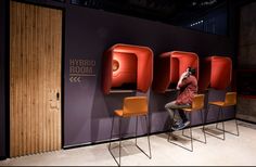 a man is sitting on a chair in front of three chairs with the word hybrid room above them