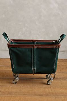 a green shopping cart sitting on top of a wooden floor next to a white wall