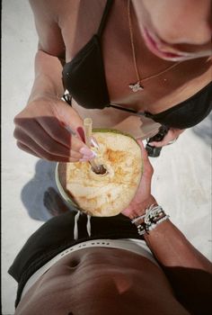 a woman holding an apple in her right hand while laying on the ground next to another person