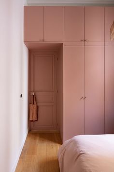 a bedroom with pink walls and wooden floors