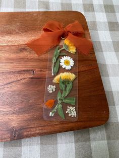 a wooden cutting board topped with flowers on top of a table