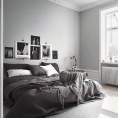 a bedroom with grey walls and pictures on the wall above the bed, along with a radiator