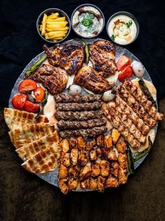 a platter filled with grilled meats, vegetables and other foods on it