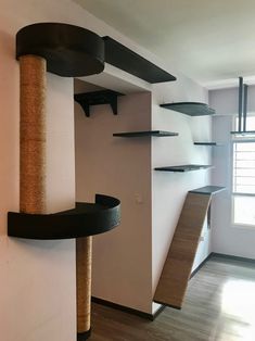 a cat tree in the corner of a living room with shelves and scratching board on the wall