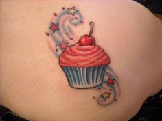 a woman's back with a tattoo of a cupcake and stars on it